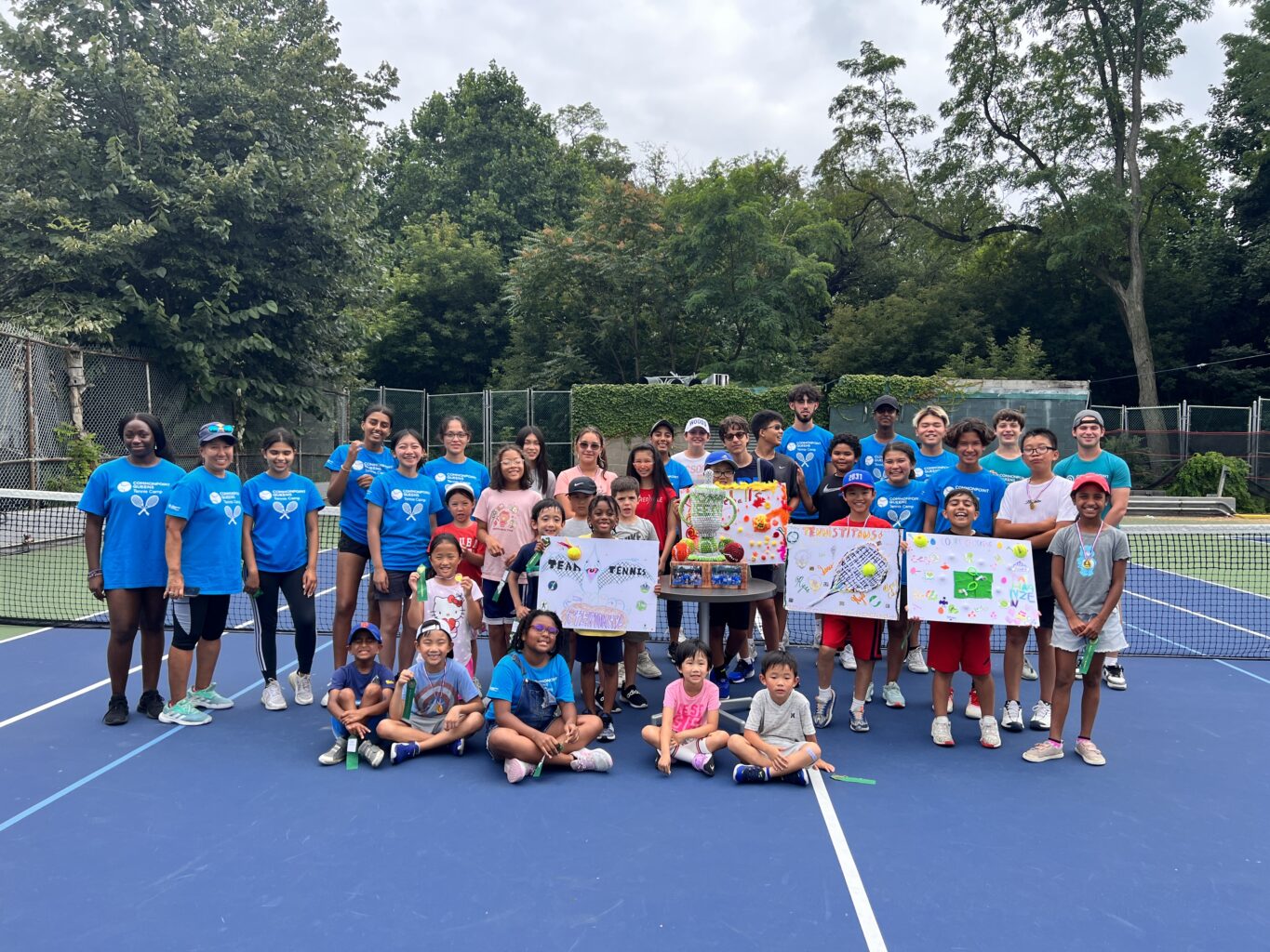 A group of children from Tennis Camp posing for a photo on a tennis court at Alley Pond.