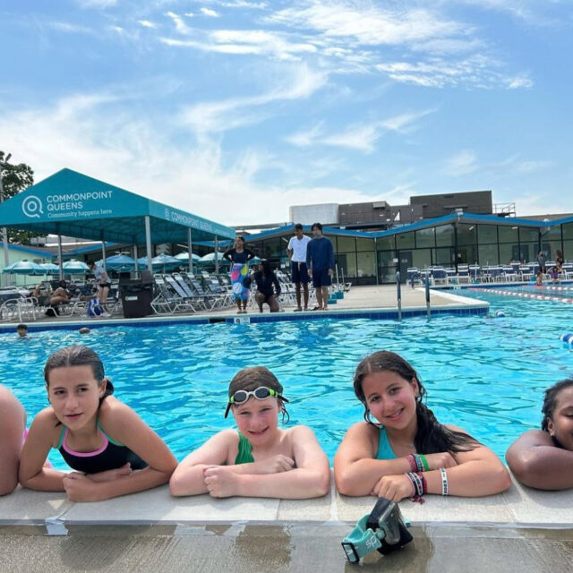 A group of girls posing for a photo in a swimming pool.