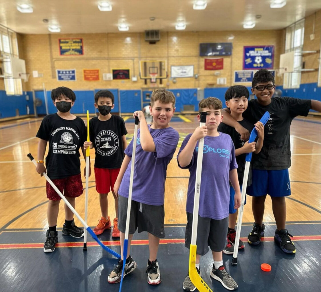 A group of boys posing for a picture with hockey sticks.
