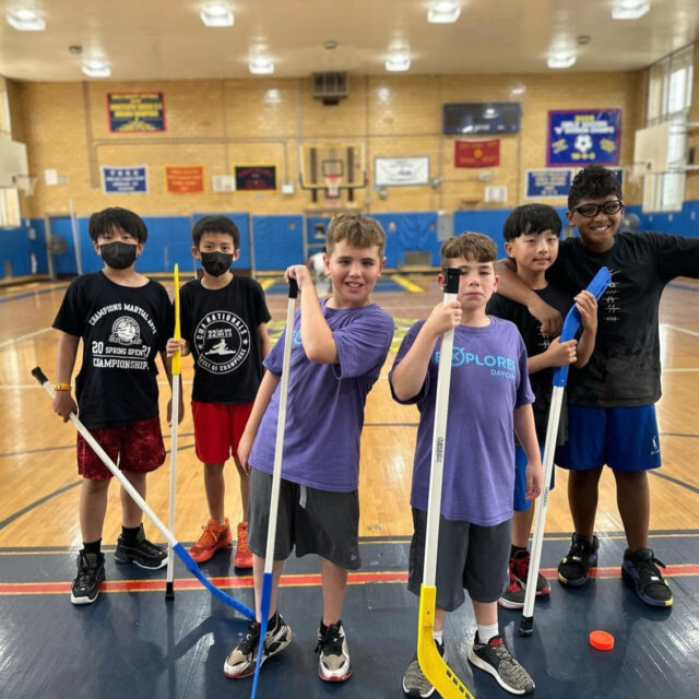 A group of boys posing for a picture with hockey sticks.