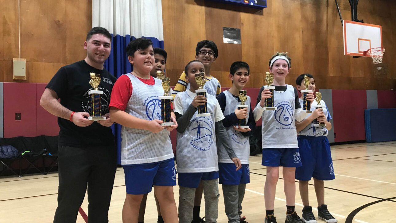 A group of boys holding trophies on a basketball court.