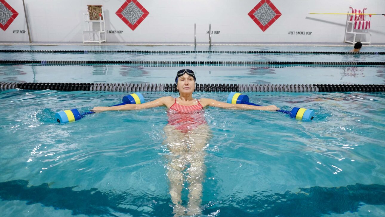 A woman floats in an indoor swimming pool.