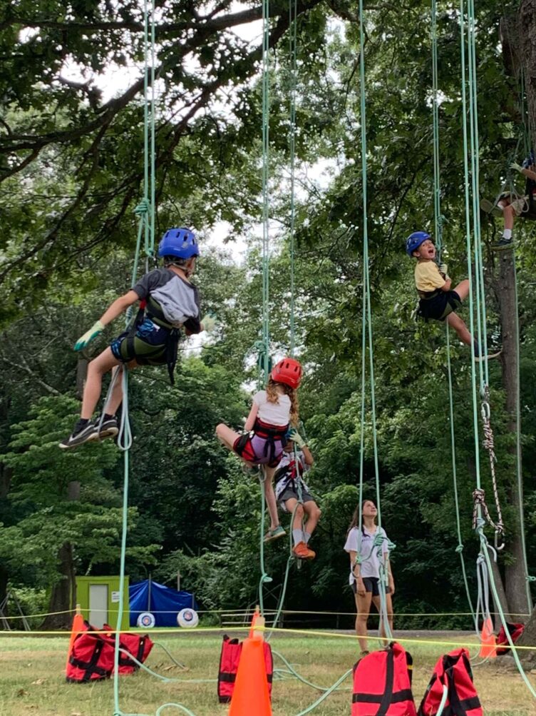 A group of children on ropes in a park.