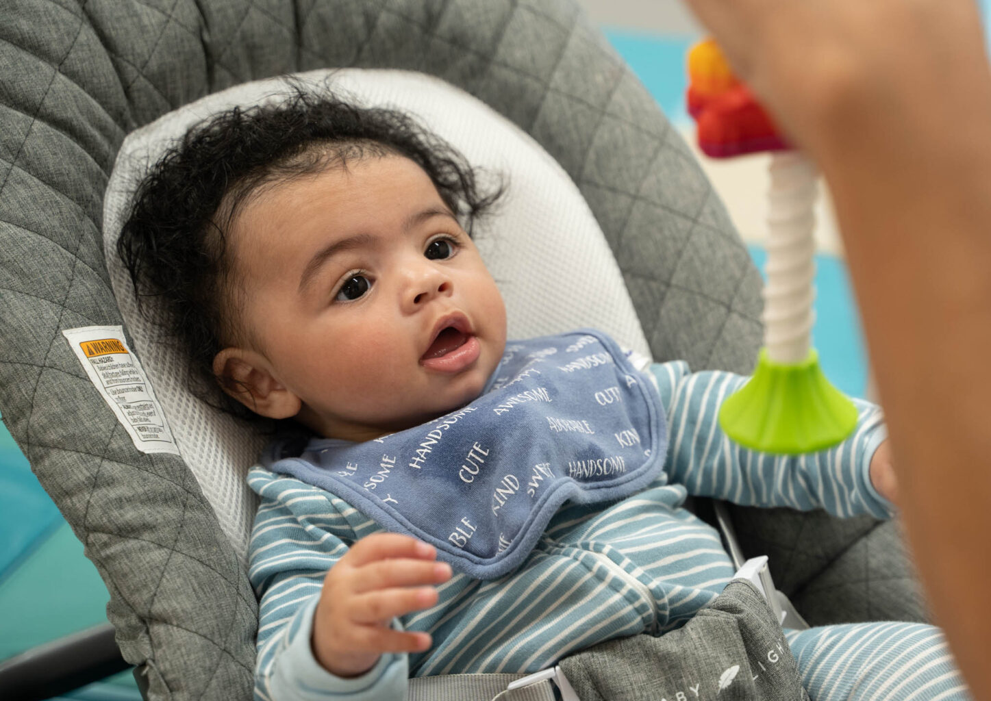 A baby in a high chair playing with a toy.