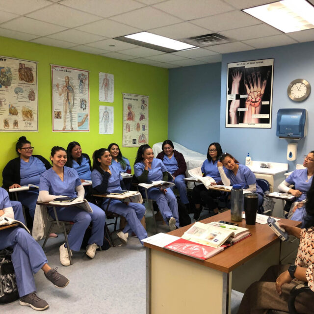 A group of women in scrubs sitting in a classroom.
