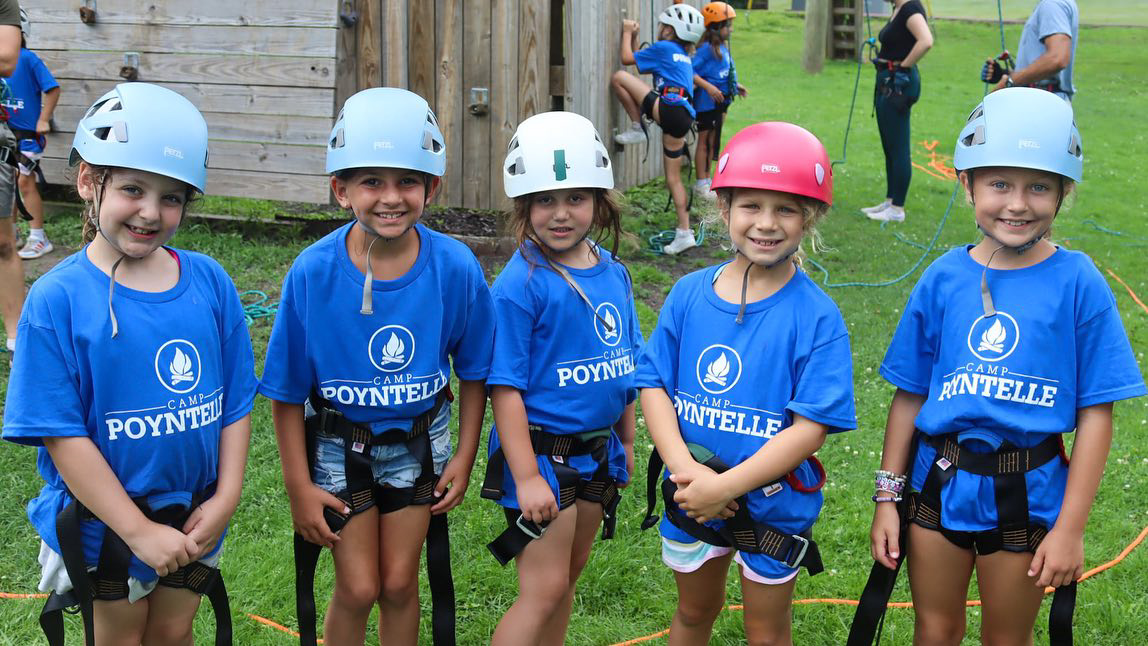 A group of young girls wearing blue shirts and helmets.