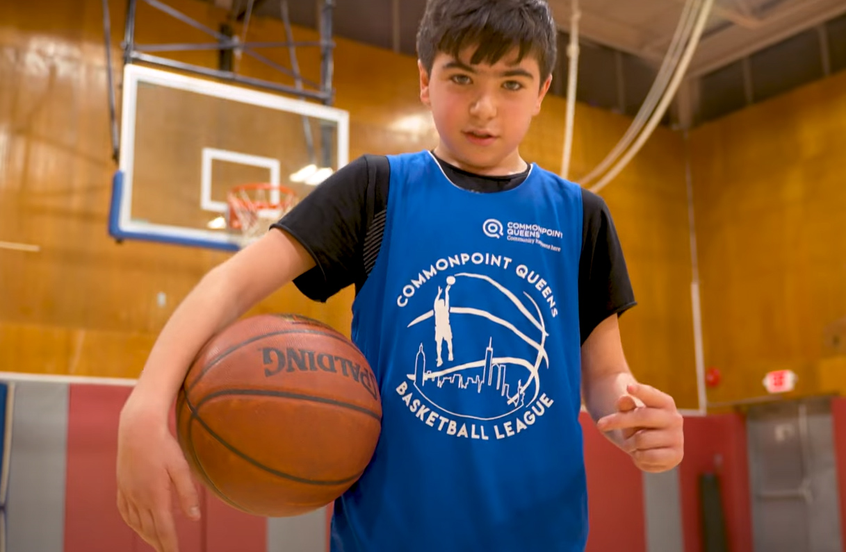 A young boy holding a basketball in a gym.