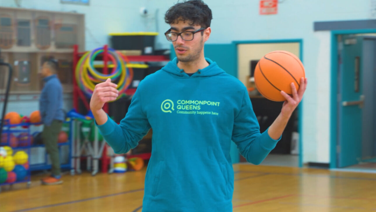 A young man holding a basketball in a gym.