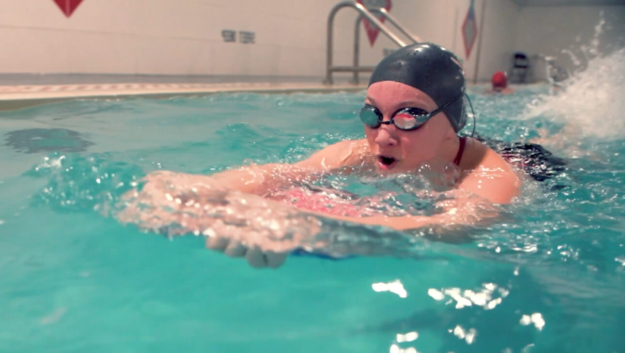 A woman swimming in a pool with goggles on.