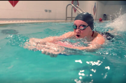 A woman swimming in a pool with goggles on.