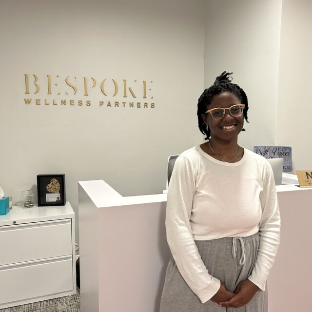 A Jewish woman standing in front of a sign that says bespoke wellness partners.