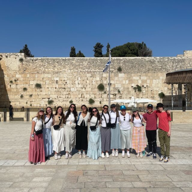 A cultural group posing in front of the western wall during a special event.