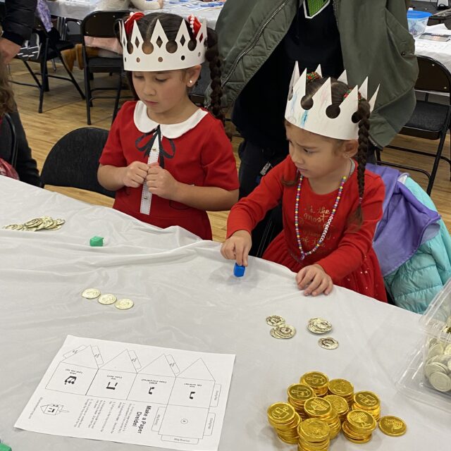 A birthday party with children sitting at a table wearing crowns on their heads.