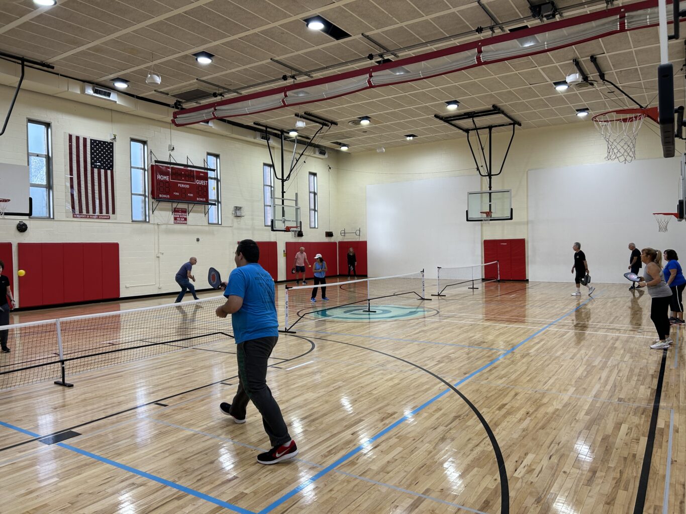 A group of adults playing badminton in a gym in Little Neck.