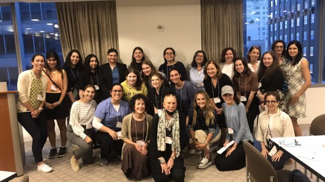 Jewish Women posing for a photo in a conference room, celebrating their JFEW Scholarship.