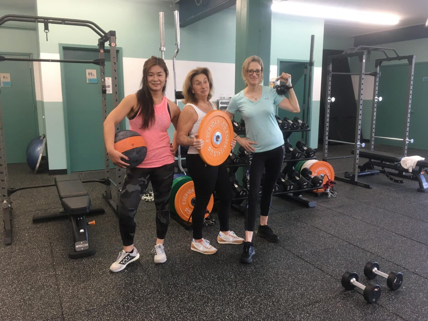 Three women posing for a photo in a gym showcasing their membership.