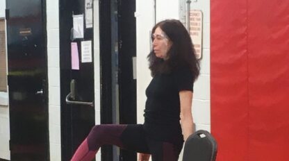A woman enjoying an on demand exercise video while sitting on a chair in a gym.