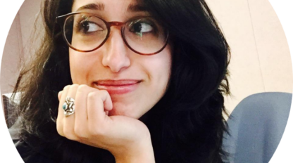 A woman wearing glasses, with an important ring on her finger.