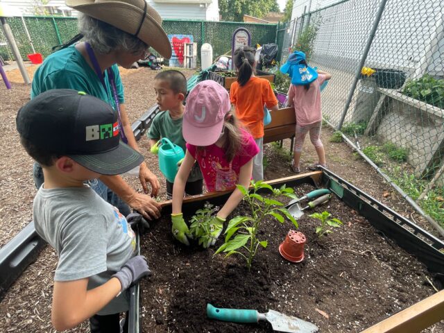 Group of children participating in a hands-on workshop for gardening with adult supervision.